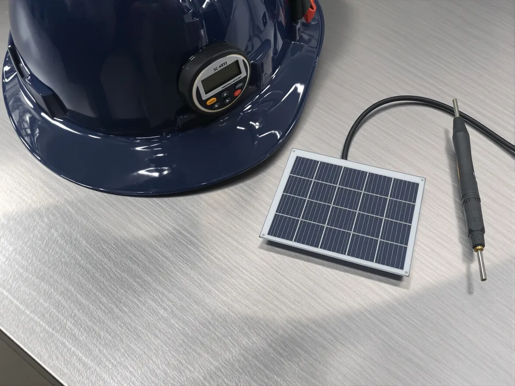 Casco, multímetro de gancho y celda solar sobre una mesa de acero