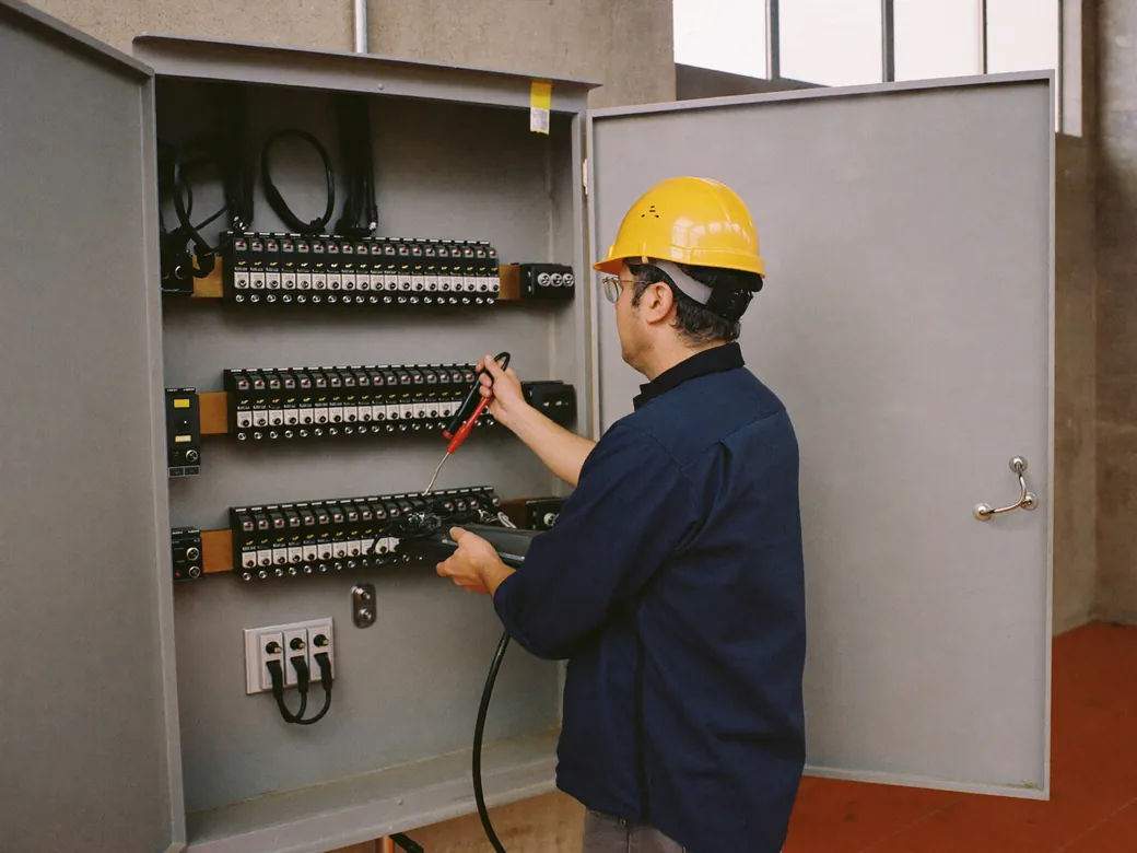 Ingeniero conectando las pinzas de un analizador de calidad de la energía en un tablero industrial