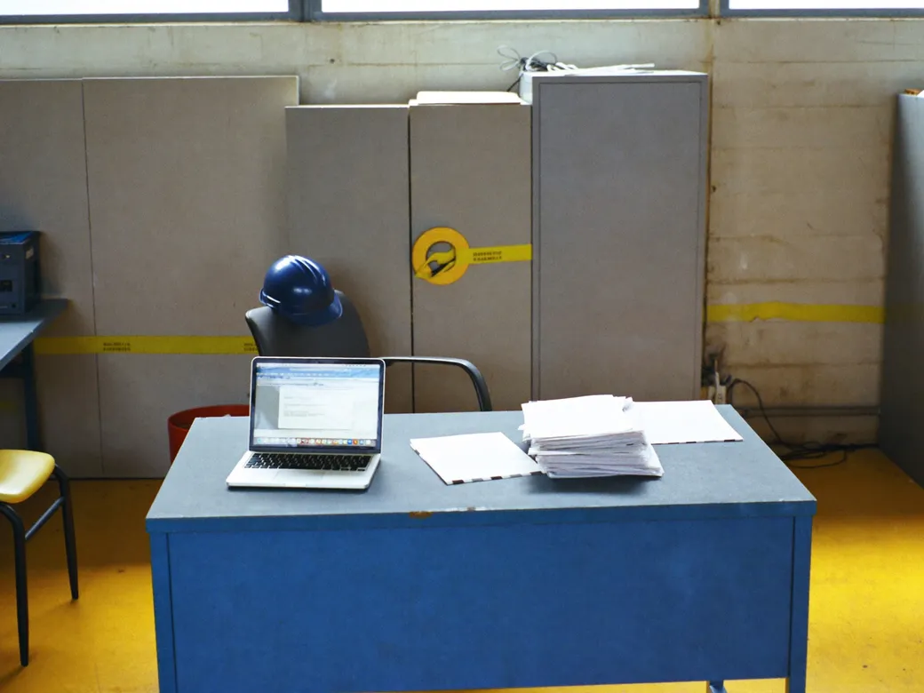 Responsable de compras revisando un recibo de CFE sobre un escritorio en una oficina de planta industrial en León, Guanajuato