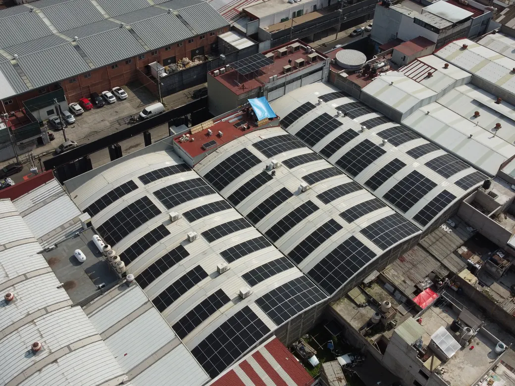 Vista frontal de las bóvedas con 437 módulos de 620 W, con camionetas en el patio